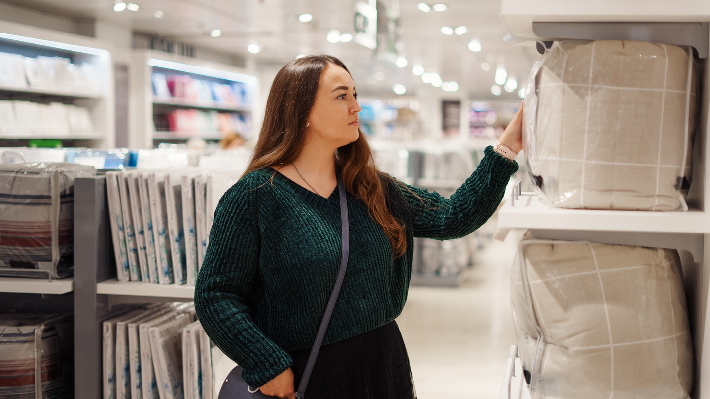 Young woman shopping for new bedding at the store