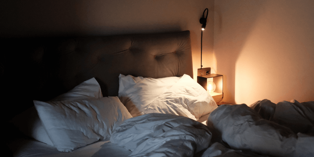 Night-time bedroom scene with soft lighting, layered duvets, and a peaceful atmosphere—perfect for winding down and better sleep.