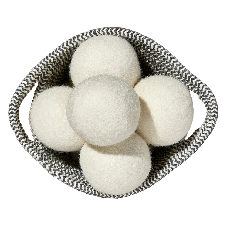 Top view of five white wool dryer balls neatly arranged inside a gray woven basket with a zigzag pattern.