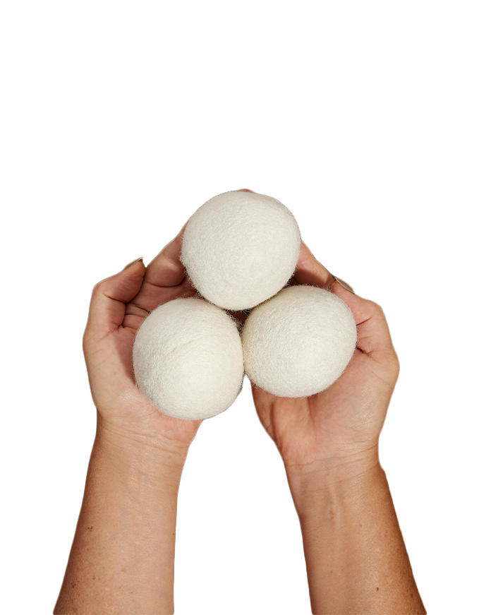 Two hands holding three white wool dryer balls, arranged in a triangular shape.