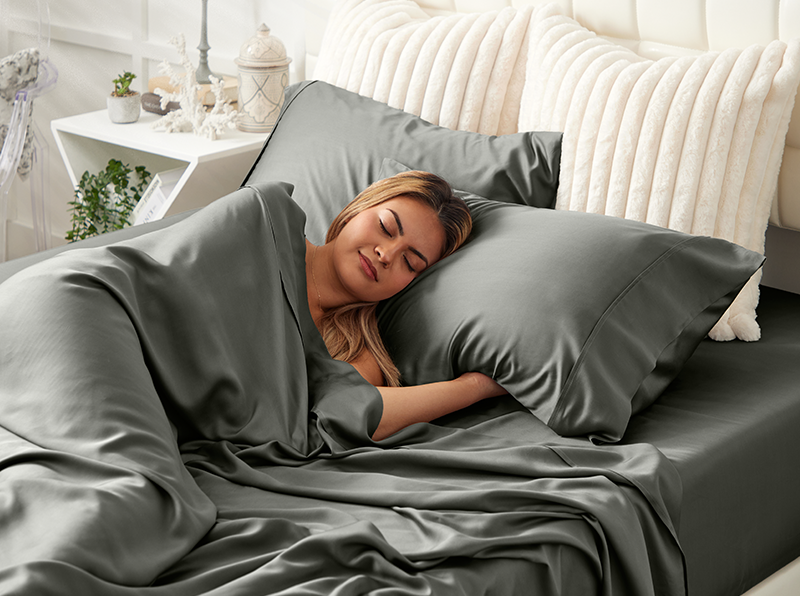 Female laying a grey sheet set and pillowcaes