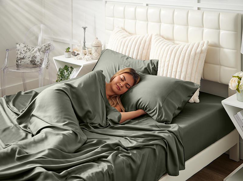 Woman sleeping under grey bedding in a well-decorated bedroom.