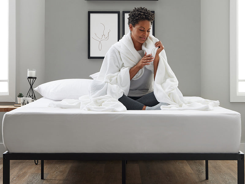 Female covered in sheets on white bed