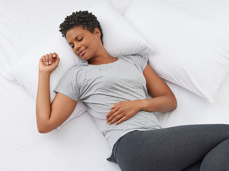 Female laying on a white bed sheets